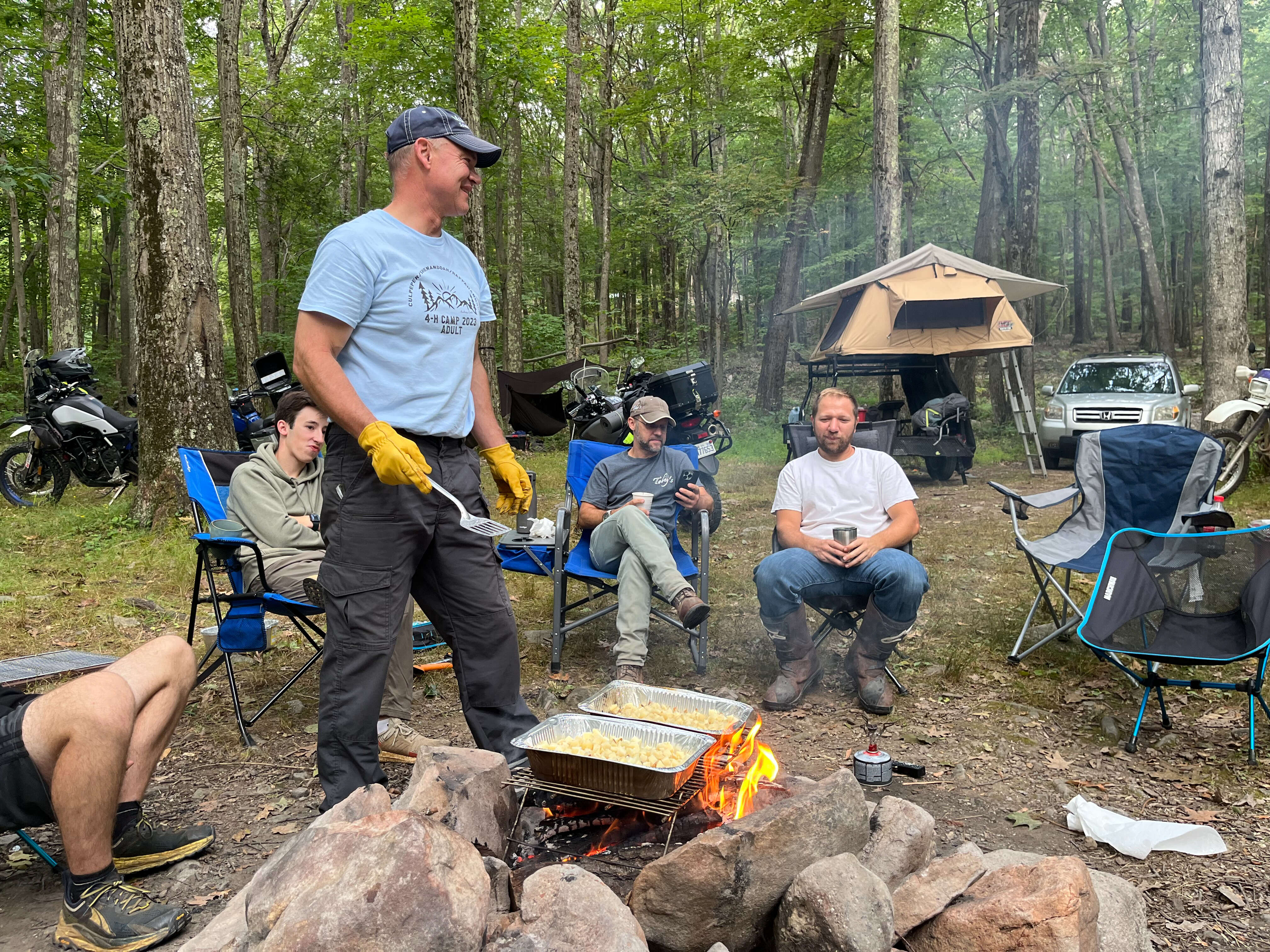 A guy cooking breakfast over the campfire.