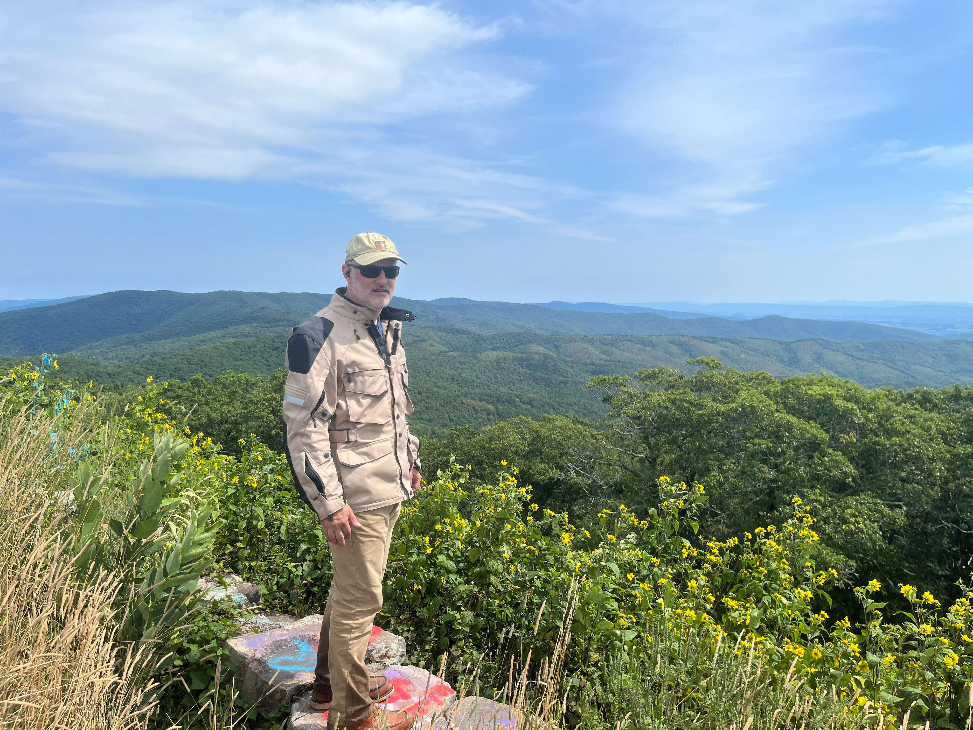 A guy standing at the edge of the Reddish Knob overlook wearing his motorcycle gear.